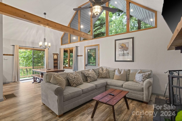 living room featuring ceiling fan with notable chandelier, hardwood / wood-style floors, high vaulted ceiling, and beam ceiling