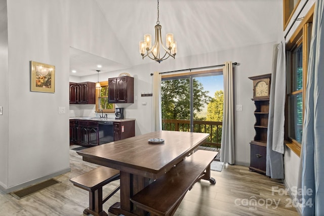 dining area with sink, high vaulted ceiling, a chandelier, and light hardwood / wood-style floors