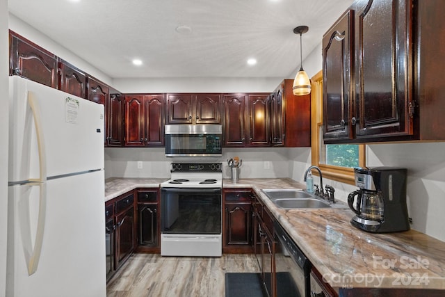 kitchen with light hardwood / wood-style floors, white appliances, sink, and hanging light fixtures