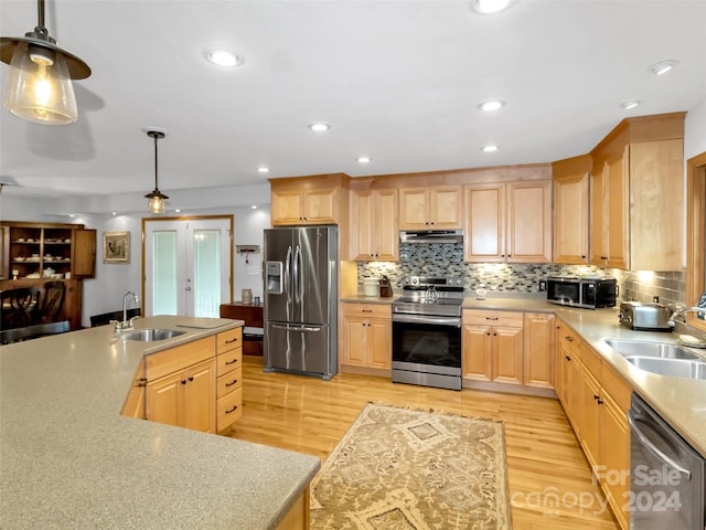 kitchen featuring decorative light fixtures, light brown cabinetry, and stainless steel appliances