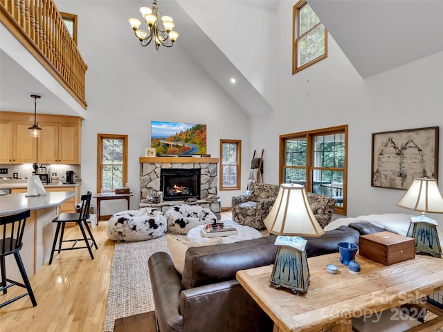 living room with a fireplace, plenty of natural light, a chandelier, and light hardwood / wood-style flooring