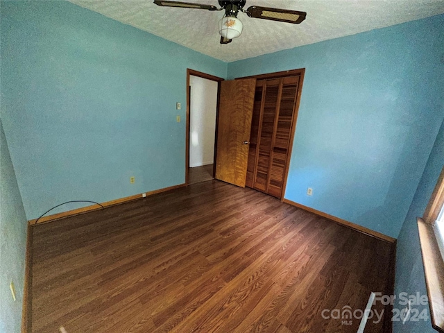 unfurnished bedroom featuring a ceiling fan, wood finished floors, baseboards, a closet, and a textured ceiling