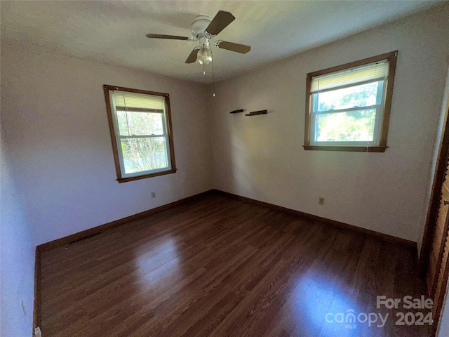 unfurnished room with visible vents, baseboards, dark wood-style flooring, and ceiling fan