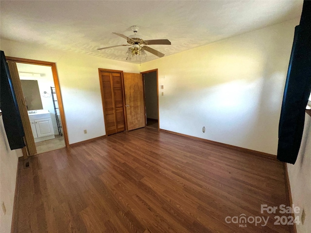 unfurnished bedroom with wood finished floors, baseboards, ceiling fan, a closet, and connected bathroom