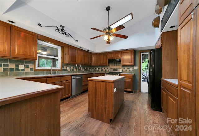 kitchen with backsplash, a kitchen island, ceiling fan, appliances with stainless steel finishes, and hardwood / wood-style flooring