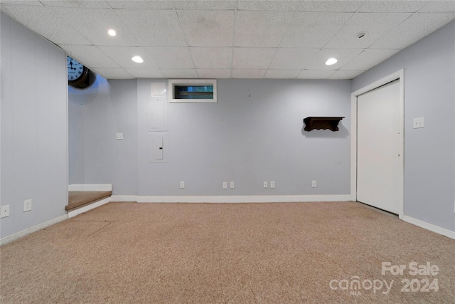 basement featuring a paneled ceiling and carpet