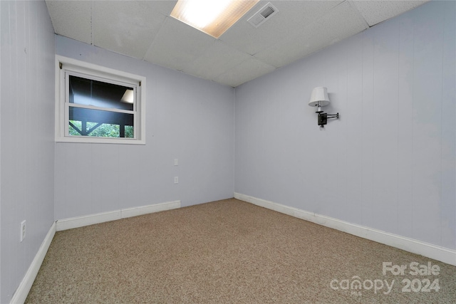 empty room featuring light colored carpet and a drop ceiling