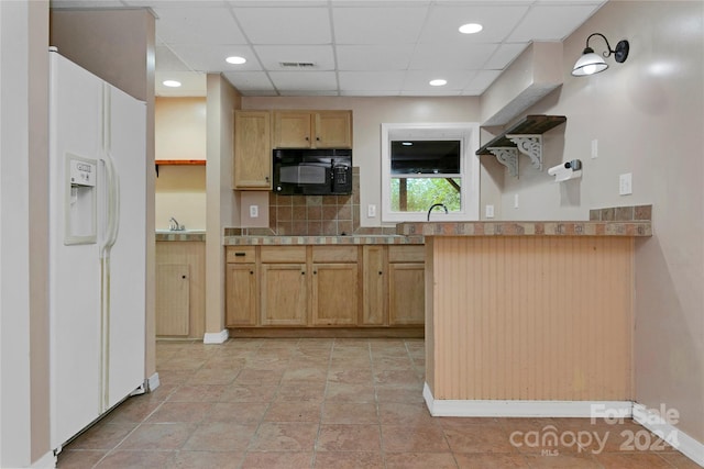 kitchen featuring white fridge with ice dispenser, a drop ceiling, tasteful backsplash, light brown cabinetry, and light tile patterned flooring