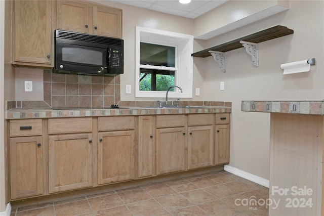 kitchen featuring black appliances, light tile patterned floors, sink, light brown cabinets, and decorative backsplash