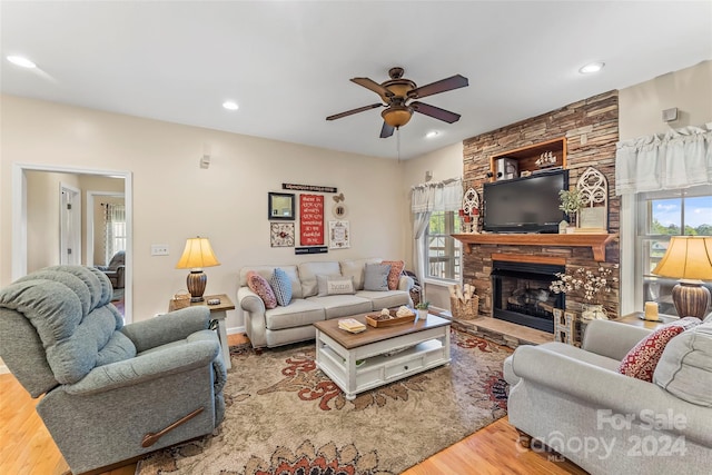 living room with ceiling fan, light wood-type flooring, and a fireplace