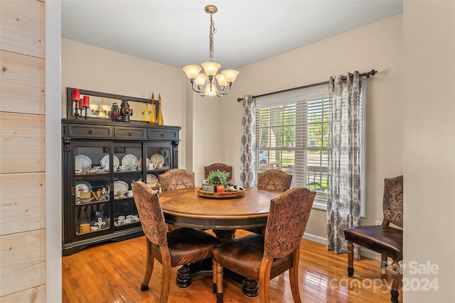 dining area with light hardwood / wood-style flooring and a notable chandelier