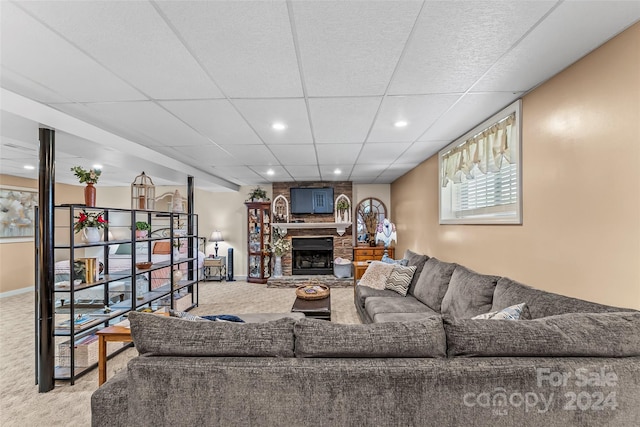 carpeted living room with a paneled ceiling and a stone fireplace