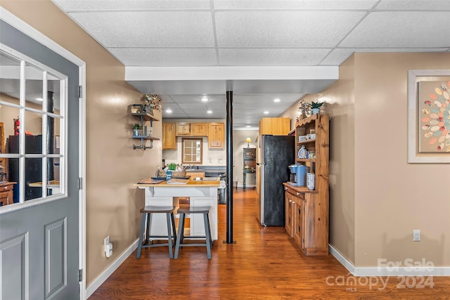 kitchen featuring dark wood-type flooring, stainless steel refrigerator, and a drop ceiling