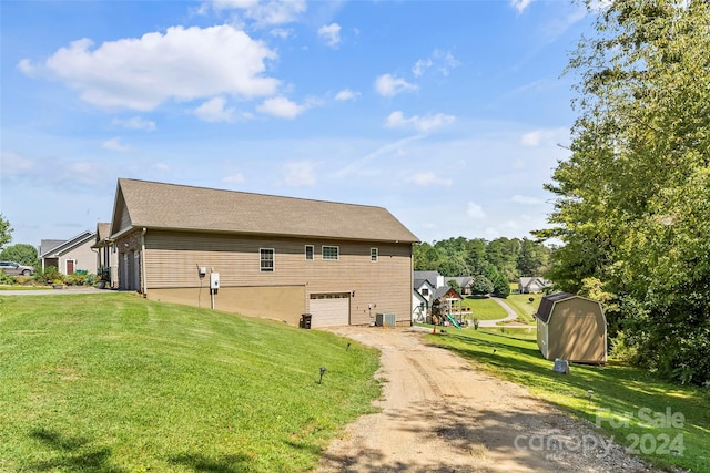 view of side of property with a garage, a playground, central AC unit, and a yard