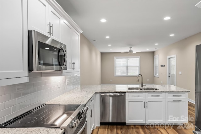 kitchen featuring stainless steel appliances, white cabinets, kitchen peninsula, and sink