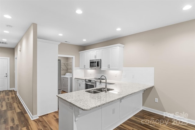 kitchen with sink, white cabinetry, separate washer and dryer, appliances with stainless steel finishes, and kitchen peninsula