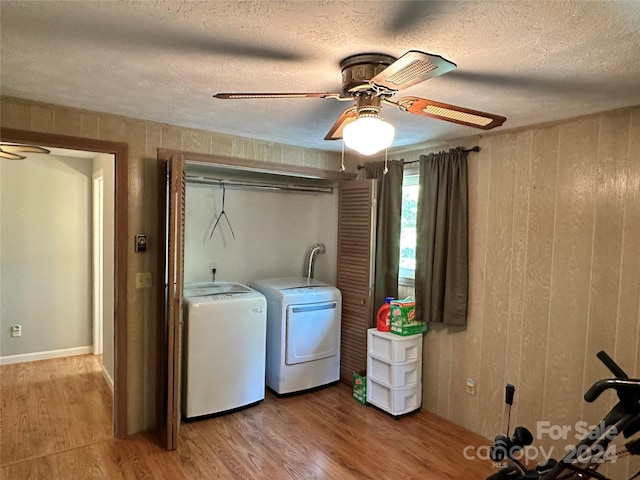 laundry room with a textured ceiling, washer and dryer, hardwood / wood-style flooring, ceiling fan, and wooden walls