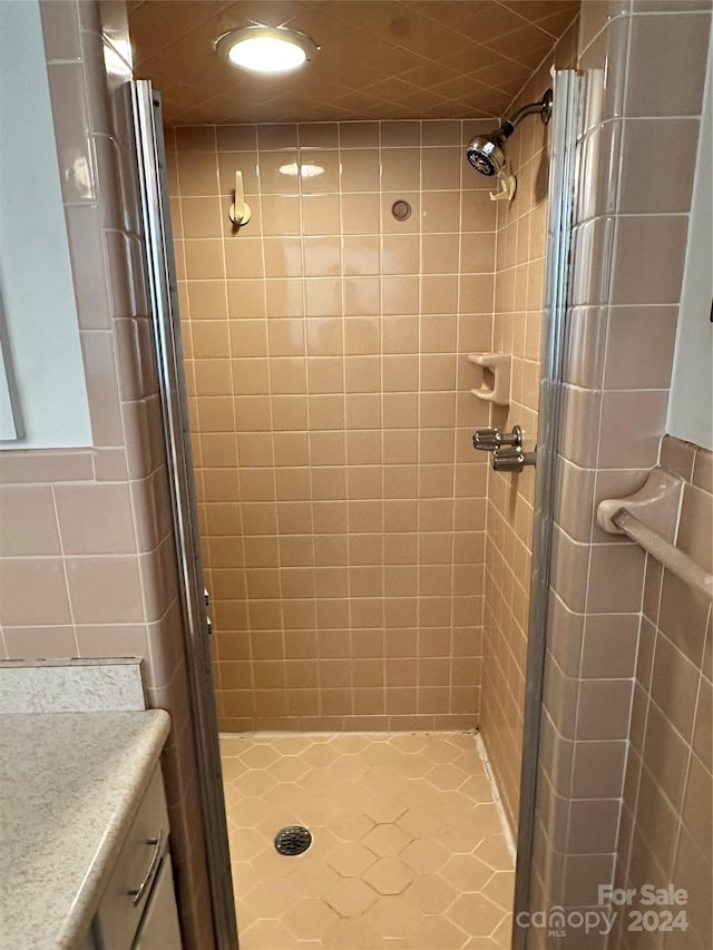 bathroom featuring tile patterned flooring, an enclosed shower, and vanity