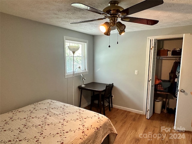 bedroom featuring a textured ceiling, light hardwood / wood-style flooring, ceiling fan, and a closet