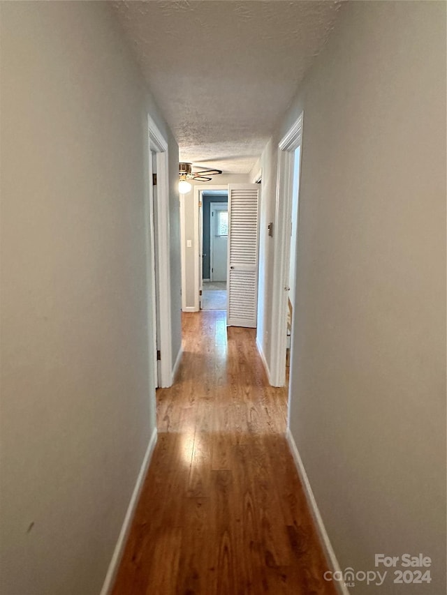 hallway featuring a textured ceiling and light hardwood / wood-style floors