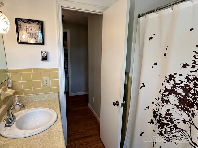 bathroom featuring walk in shower, tile walls, hardwood / wood-style floors, and sink