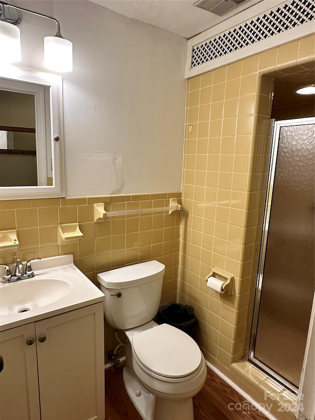 bathroom with a shower with door, vanity, tile walls, toilet, and hardwood / wood-style flooring