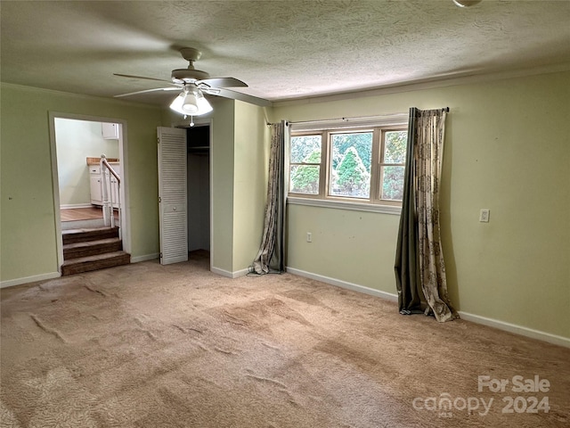 unfurnished bedroom featuring light carpet, a textured ceiling, ceiling fan, and a closet