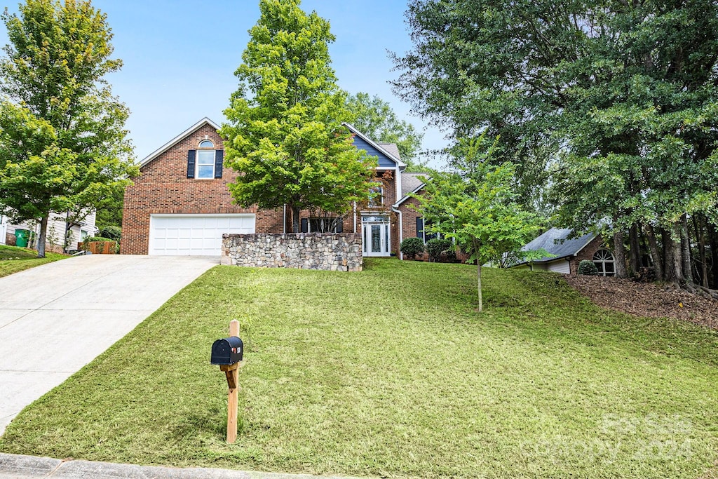 view of property hidden behind natural elements featuring a garage and a front yard