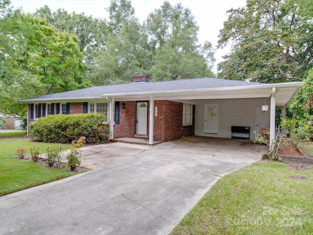 ranch-style home featuring a front yard, driveway, a chimney, a carport, and brick siding