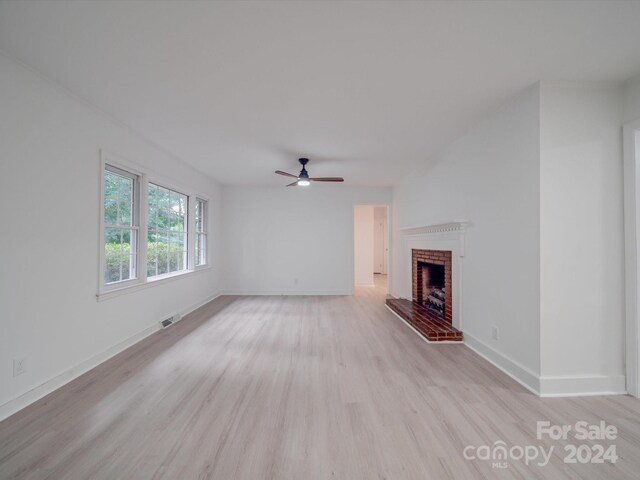 unfurnished living room with visible vents, a brick fireplace, baseboards, ceiling fan, and light wood-style flooring