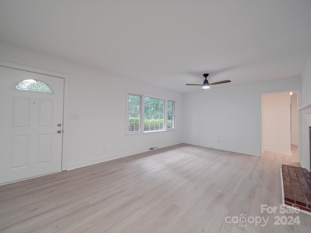 foyer featuring a brick fireplace, ceiling fan, and light hardwood / wood-style floors