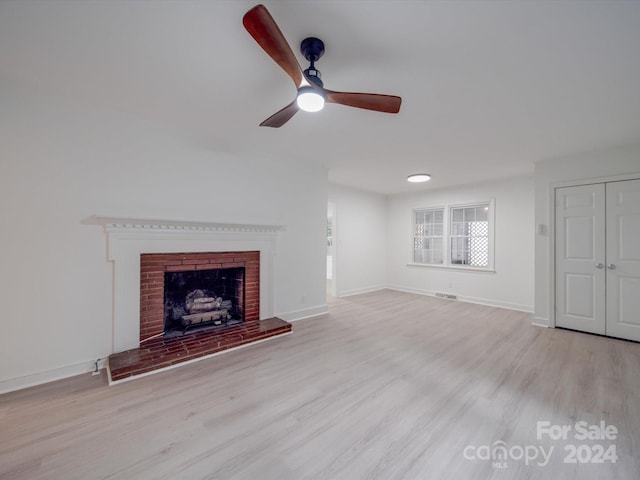 unfurnished living room featuring light hardwood / wood-style flooring, ceiling fan, and a brick fireplace