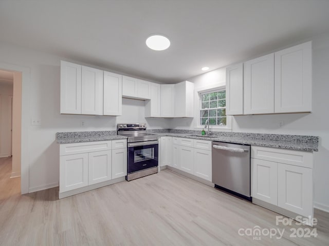 kitchen featuring light stone countertops, light hardwood / wood-style flooring, appliances with stainless steel finishes, sink, and white cabinets