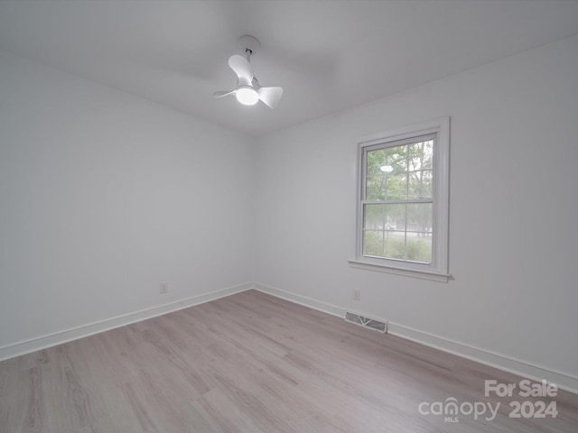 unfurnished room featuring ceiling fan, wood finished floors, visible vents, and baseboards