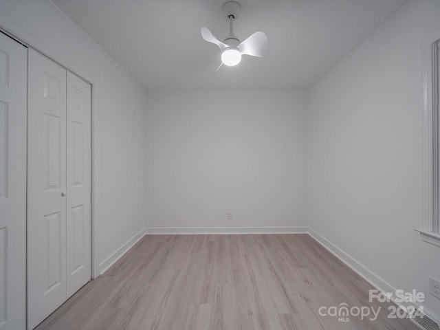 unfurnished bedroom with a closet, baseboards, a ceiling fan, and light wood finished floors