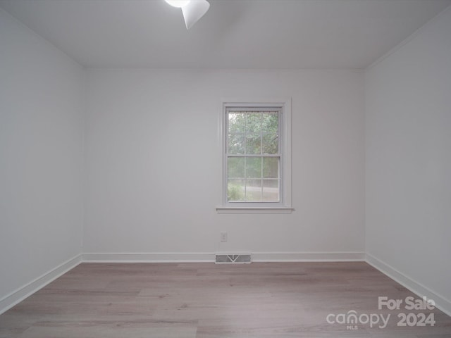 empty room featuring visible vents, baseboards, and wood finished floors