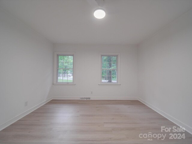 spare room featuring visible vents, light wood-style floors, and baseboards