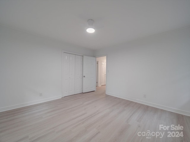 unfurnished bedroom with a closet, baseboards, and light wood-style flooring