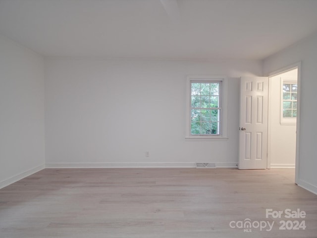 empty room featuring visible vents, baseboards, and light wood-style floors