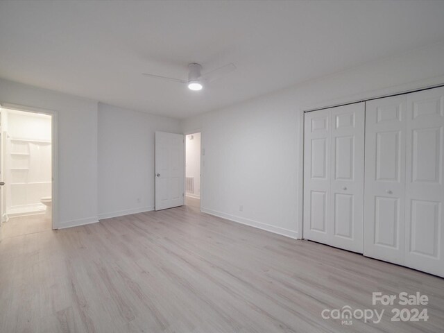 unfurnished bedroom with light hardwood / wood-style flooring, ensuite bathroom, ceiling fan, and a closet