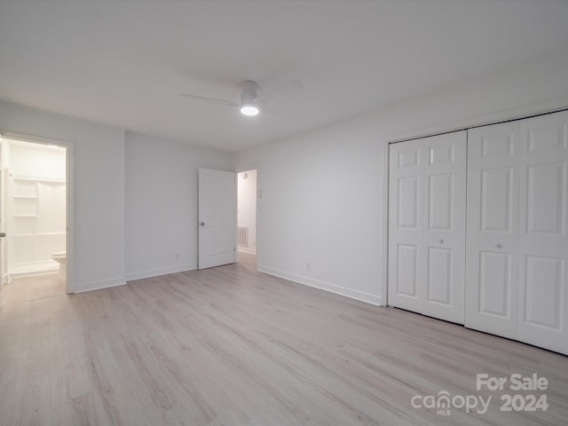 unfurnished bedroom featuring light wood-style floors, baseboards, and a closet