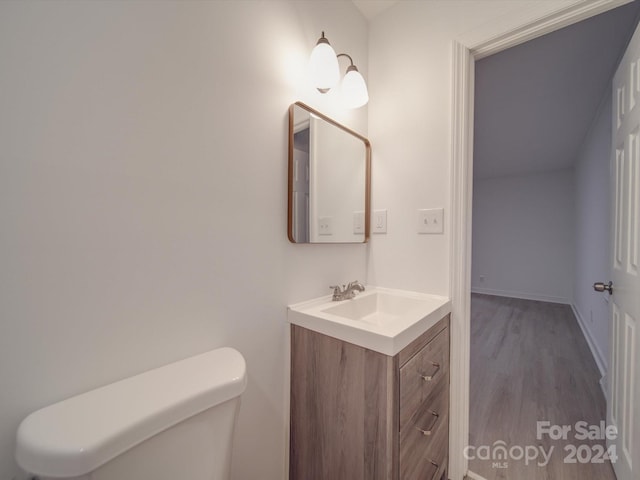 bathroom with baseboards, toilet, wood finished floors, and vanity