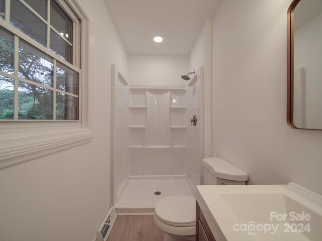 bathroom with vanity, toilet, walk in shower, and hardwood / wood-style floors