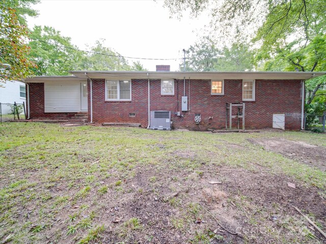 rear view of property with a yard, brick siding, central AC, and fence