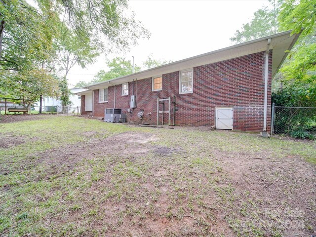 rear view of property with a yard and central AC unit