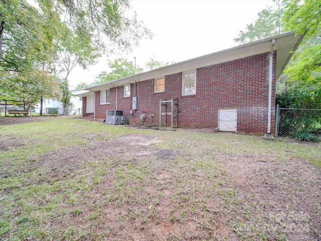 back of property with a yard, fence, and brick siding