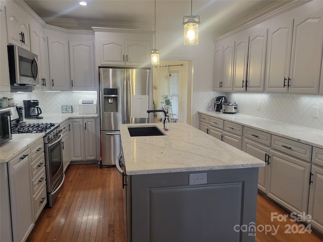 kitchen featuring decorative light fixtures, stainless steel appliances, backsplash, and an island with sink