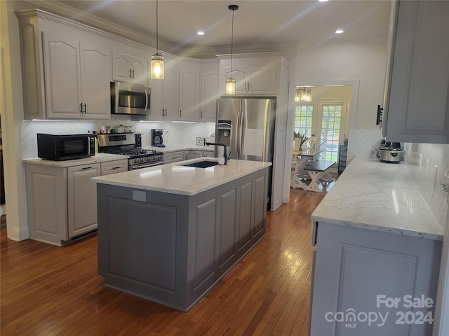 kitchen with dark wood-type flooring, backsplash, sink, pendant lighting, and appliances with stainless steel finishes