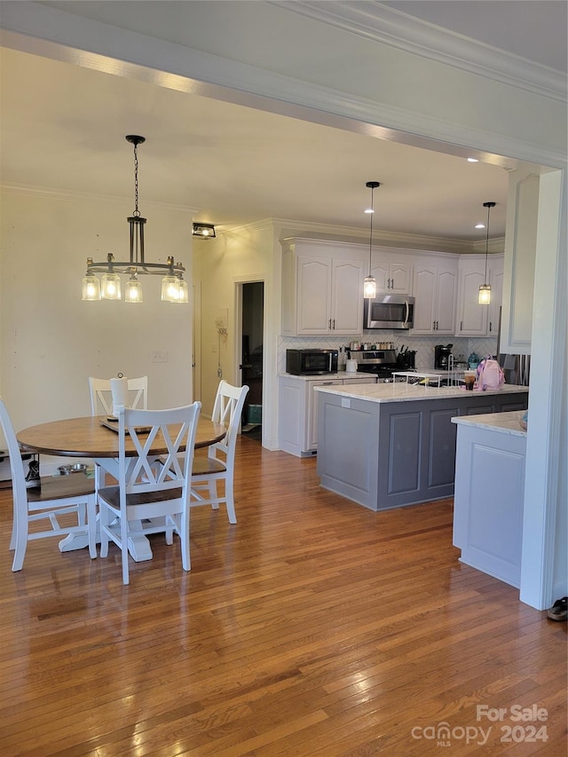 kitchen with light hardwood / wood-style floors, stainless steel appliances, pendant lighting, and white cabinets