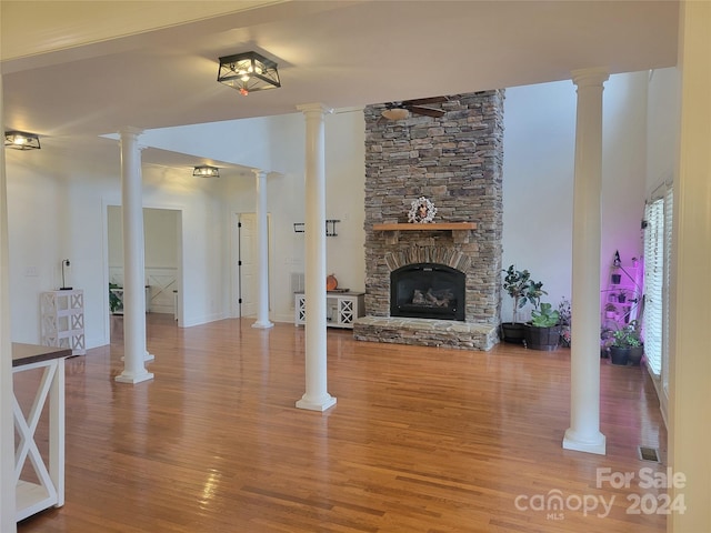 unfurnished living room featuring a stone fireplace, wood-type flooring, and ceiling fan